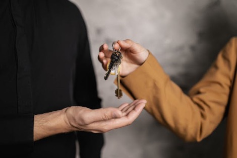A person giving house keys to a man dressed in black